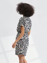 Vestido corto con estampado floral en tonos azul y blanco, con cuello en V, mangas cortas y lazo en la cintura.