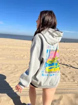 Canguro negro con capucha y cordones ajustables. Estampa en la espalda con el texto "Chema Surf Trip" y dibujos de un sol, una tabla de surf, una carpa y otros elementos relacionados con el surf.