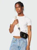 Bolso bandolera mini Marc Jacobs de cuero negro con cierre dorado y correa de tela con logo de la marca.