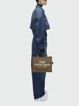Bolso tote mediano color beige con estampado frontal del logo "The Tote Bag Marc Jacobs" en blanco. Tiene doble asa corta y correa larga extraíble de tela azul marino.