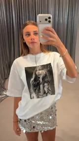 Remera blanca de algodón, corte oversize, con estampa fotográfica en blanco y negro de una mujer con cabello largo y accesorios.