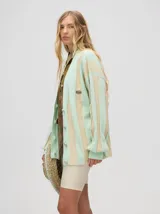 Cardigan a rayas horizontales en tonos beige y negro, de corte holgado y abierto, con botones metálicos y logo MUTMA bordado en el frente.