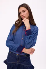 Camisa de denim azul con cuello y puños con detalles de crochet en azul marino y rojo.