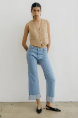 Pantalón de jean azul oscuro con corte acampanado, tiro medio y dobladillo en el ruedo. Presenta costuras marcadas en el frente y estampado abstracto en tonos grises y blancos en el interior del dobladillo.