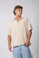 Camisa de lino color blanco, de manga corta, con cuello clásico y cierre frontal con botones.