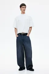 Pantalón de jean azul oscuro de corte holgado, con tiro bajo, cinco bolsillos y pierna extra ancha con pliegues en el tobillo.