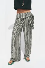 Pantalón de tiro alto con nudo delantero, de pernera ancha y estampado a rayas verticales en blanco y negro.