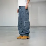 Pantalón jean azul de corte ancho, con bolsillos laterales y diseño de parches con bordes desflecados.