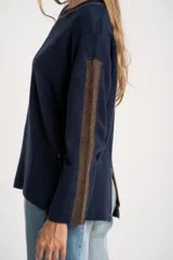 Sweater de punto azul marino con calce oversize. Presenta un detalle de franja vertical color marrón en la parte exterior de ambas mangas y un ribete fino dorado en el escote redondo.