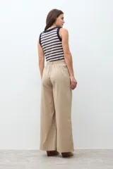Pantalón de mujer color beige, tiro alto, con pliegues (pinzas) frontales y corte ancho y recto en las piernas.