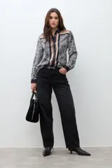 Camisa de manga larga con cuello camisero, estampado de cebra y detalles verticales en tonos negro, marrón y beige en el frente.