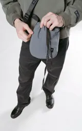 Bolso gris tipo drawstring con correa larga negra con logo de la marca en blanco.