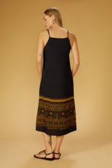 Vestido midi negro con estampado de palmeras y motivos geométricos en color ocre. Diseño de tirantes finos y corte recto.