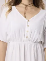 Vestido corto blanco de algodón y lino, con escote en V, mangas cortas y cintura elastizada. Cierre frontal con botones.