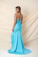 Vestido largo de fiesta color celeste, con breteles finos cruzados en la espalda, escote en V, drapeado en la parte superior, volados desde la cintura y abertura lateral.