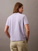 Remera de manga corta color lila de algodón con cuello redondo y logo Calvin Klein aterciopelado en color amarillo en el pecho.