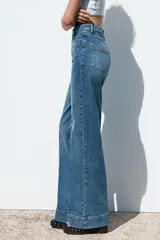 Pantalón de jean de tiro alto con bolsillos frontales y traseros. Corte recto y cierre frontal con cremallera y botón.
