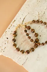 Pulsera elástica con cuentas de piedra natural ojo de tigre de 4mm y detalles de bolitas doradas.