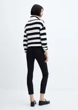 Pantalón negro de corte skinny y largo cropped, confeccionado en tejido fluido con forro interior. Presenta tiro medio, trabillas, bolsillos laterales y traseros de ribete. Cierre frontal con cremallera y botón.