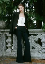 Pantalón negro de vestir, tiro medio, corte wide leg y aberturas laterales en el ruedo.