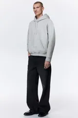 Canguro gris con capucha forrada con cordón ajustable, hombros caídos, bolsillo tipo canguro y corte holgado.