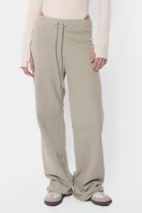 Pantalón de jogging color beige, de frisa y corte relajado. Con cintura de rib al tono, cordones con punteras metálicas y ojalillos personalizados de marca. Detalle de bordado a contratono en ambos laterales de pierna.