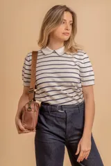 Bandolera color rosa viejo con detalles en cuero marrón claro, múltiples cremalleras metálicas y herrajes plateados. Incluye correa ancha ajustable con el logo de la marca.