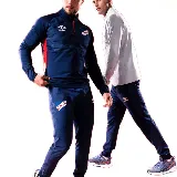 Buzo de entrenamiento azul marino con cierre parcial rojo, escudo del Club Nacional de Football y logo de Umbro en el pecho.