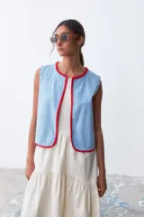 Chaleco celeste de denim con terminaciones en crochet rojo.