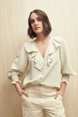 Camisa blanca a rayas verticales, con escote en V, mangas 3/4 con puños elastizados y volados.