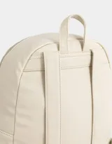 Mochila de cuerina color crudo con bolsillo frontal con cierre y charm decorativo con cierre. Cuenta con correas regulables y manija superior.