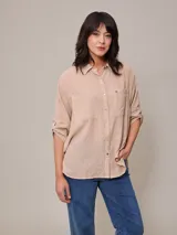Camisa color beige de algodón y lino, con cuello clásico, cierre frontal con botones, mangas largas con puños abotonados, dos bolsillos con solapa en el pecho y corte holgado.
