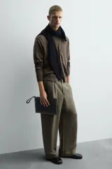Bolso tipo sobre negro, con compartimento principal con cierre de cremallera, bolsillo interno con cremallera, bolsillo frontal con cremallera y asa de mano.