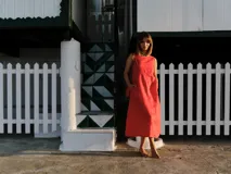 Vestido midi color crudo, de lino, con escote redondo, sin mangas y bolsillos laterales.
