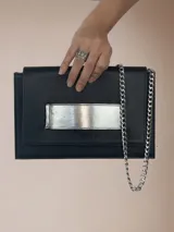 Sobre de cuero negro con detalles plateados, incluye cadena removible de un metro.