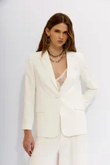 Blazer color blanco hueso, con solapas de muesca, cierre frontal con un botón y bolsillos delanteros con solapa.