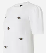Blusa blanca de algodón con cuello redondo, mangas cortas abullonadas y bordados de abejas.
