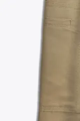 Pantalón color beige de tiro medio con trabillas, bolsillos laterales, de plastrón en pierna y detalle de solapas en espalda. Detalle de pinzas en delantero y cierre frontal con cremallera y ganchos metálicos.
