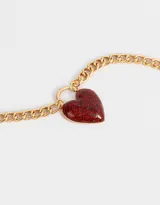 Collar corto con cadena dorada de eslabones gruesos y dije de corazón rojo brillante.