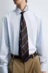 Camisa celeste de algodón con estructura twill, corte regular, cuello solapa, manga larga con puños abotonados y cierre frontal con botones.