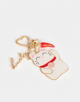 Llavero metálico con dije esmaltado de gatito de la suerte, cascabel y pimiento rojo. Incluye mosquetón en forma de corazón y dije con la palabra "Lucky".