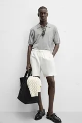 Bermuda negra regular fit confeccionada en tejido de algodón con estructura. Cintura elástica ajustable con cordón, bolsillos laterales y bolsillo trasero de vivo.
