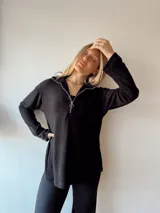 Sweater negro de punto canalé con cuello polo y etiqueta de cuero sintético en la espalda.