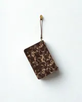 Sobre con cierre de cremallera y correa de mano, con estampado camuflado en tonos marrón, verde y beige.