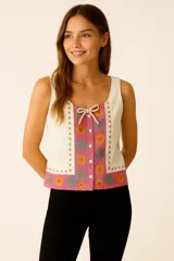 Blusa sin mangas de lino color crema con estampado de flores en tonos rosados, amarillos y celestes. Tiene cuello cuadrado, lazo decorativo y cierre frontal con botones.