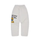 Pantalón de jogging gris con estampado del logo de Corteiz Lion en azul y amarillo en la pierna izquierda.