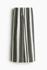 Pantalón palazzo de punto con textura a rayas verticales en blanco y negro. Tiene tiro alto, piernas rectas, elástico en la cintura y cordón para ajustar.