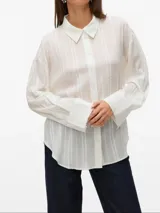Camisa blanca traslúcida con textura de líneas verticales, cuello clásico, cierre frontal con botones, mangas largas con puños abotonados y corte holgado.