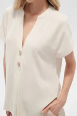 Blusa color crudo de viscosa, corte holgado, con cuello en v y cierre frontal con dos botones de madera.