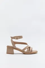Sandalia color nude con tiras cruzadas y pulsera al tobillo con hebilla metálica. Taco ancho medio.